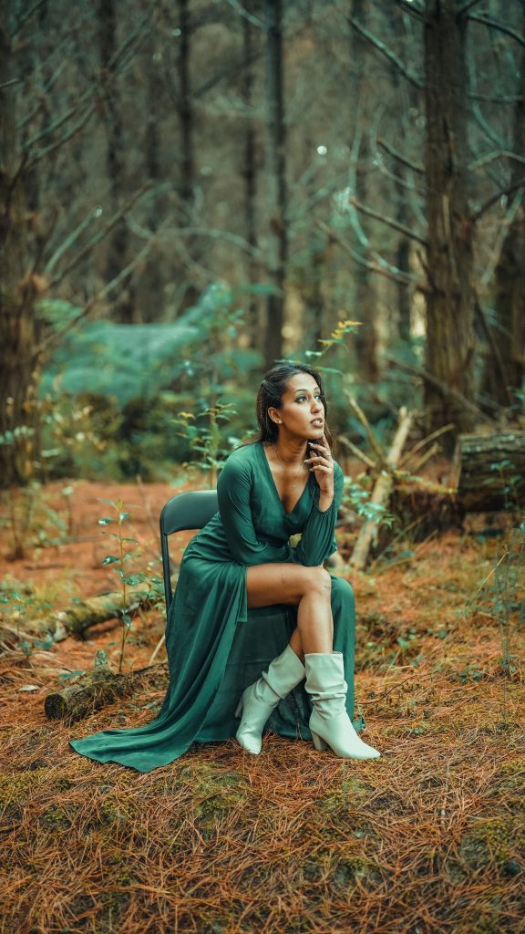 Imagem mulher de vestido e bota verde sentada em uma cadeira na natureza