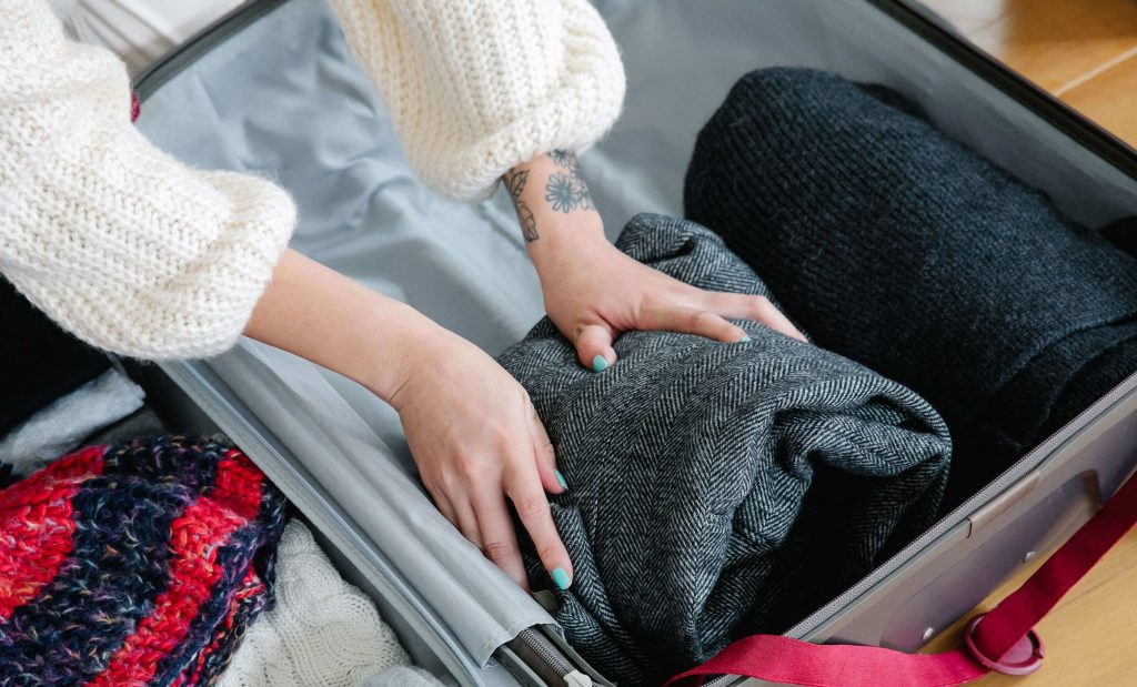 Imagem mãos femininas guardando roupas em mala de viagem 