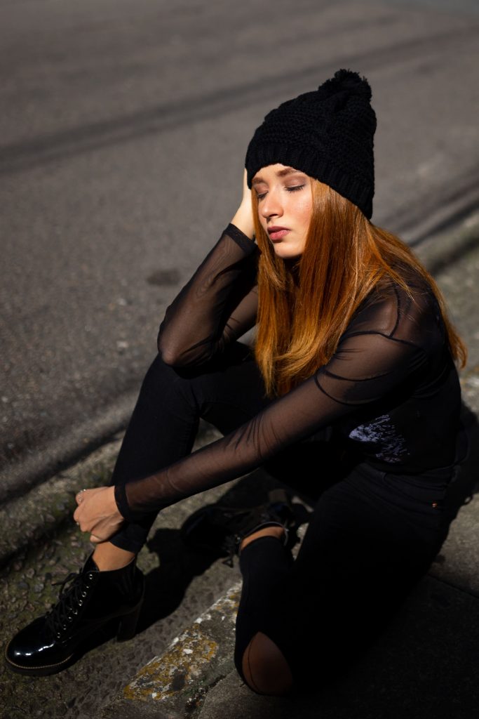 Imagem mulher sentada no chão com roupas e touca preta
