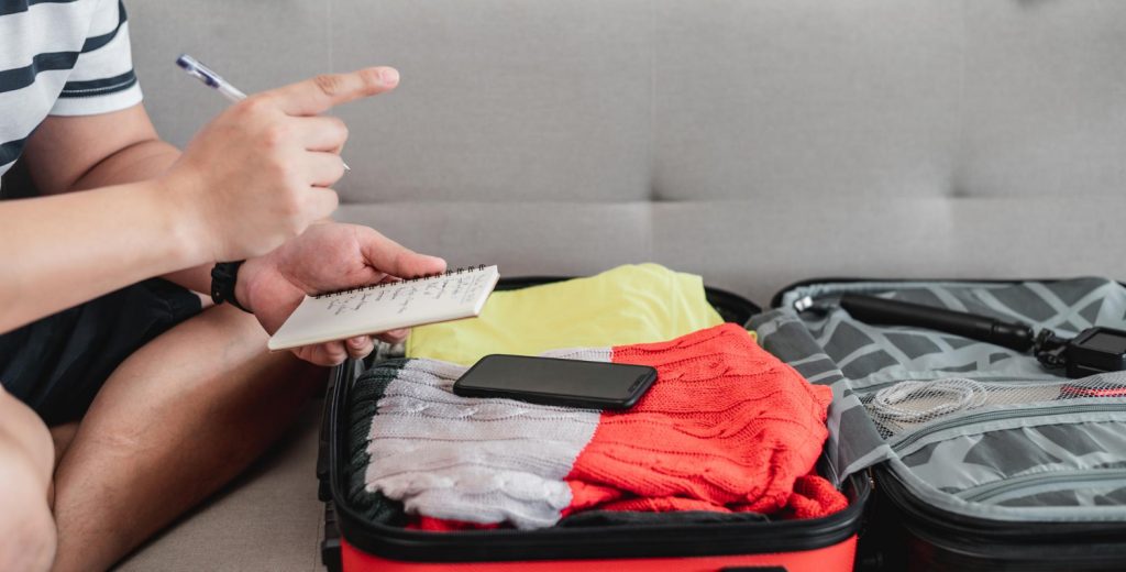 imagem de uma pessoa fazendo anotações e organizando mala para viajar